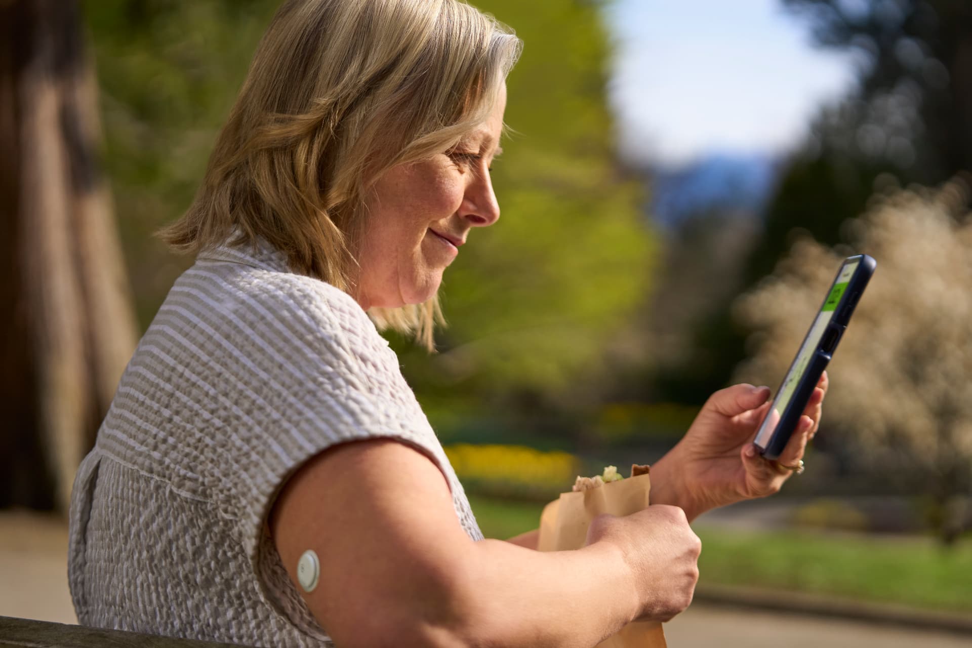 Woman viewing glucose information on her phone outdoors